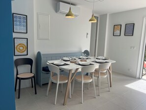A modern dining area with a round table, white chairs, and a blue bench.