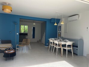 A modern living space with a dining area, a sofa, a floor lamp, and a staircase leading to another room.