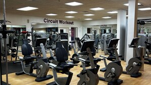Una palestra con diverse macchine per esercizi, un cartello con su scritto 'Circuit Workout' e un pavimento in legno.
