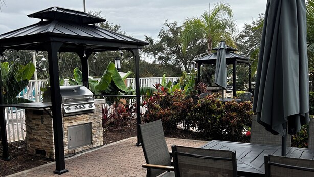 Una terrazza esterna con pavimento in piastrelle esagonali, un barbecue e un gazebo.