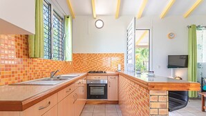 A kitchen with a tiled backsplash, wooden cabinets, a built-in oven, and a sink. - ALAMANDA (1 to 3 people) (DESHAIES)