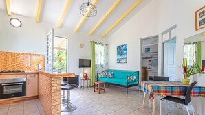 A spacious living area with a kitchen, a dining table, and a sofa. - ALAMANDA (1 to 3 people) (DESHAIES)