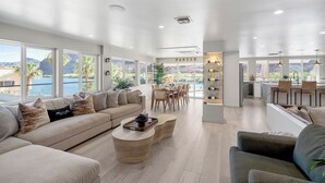 Ein geräumiger Wohnbereich mit einer großen Couch, einem Couchtisch sowie einem Essbereich mit Stühlen und einem Tisch.