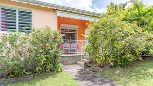 A house with a porch, a small garden, and a pathway leading to the entrance. - BALISIER (2 to 4 people) (DESHAIES)