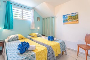 A room with two beds, a painting of a beach, and a wooden chair. - IXORA (2 to 4 people) (DESHAIES)