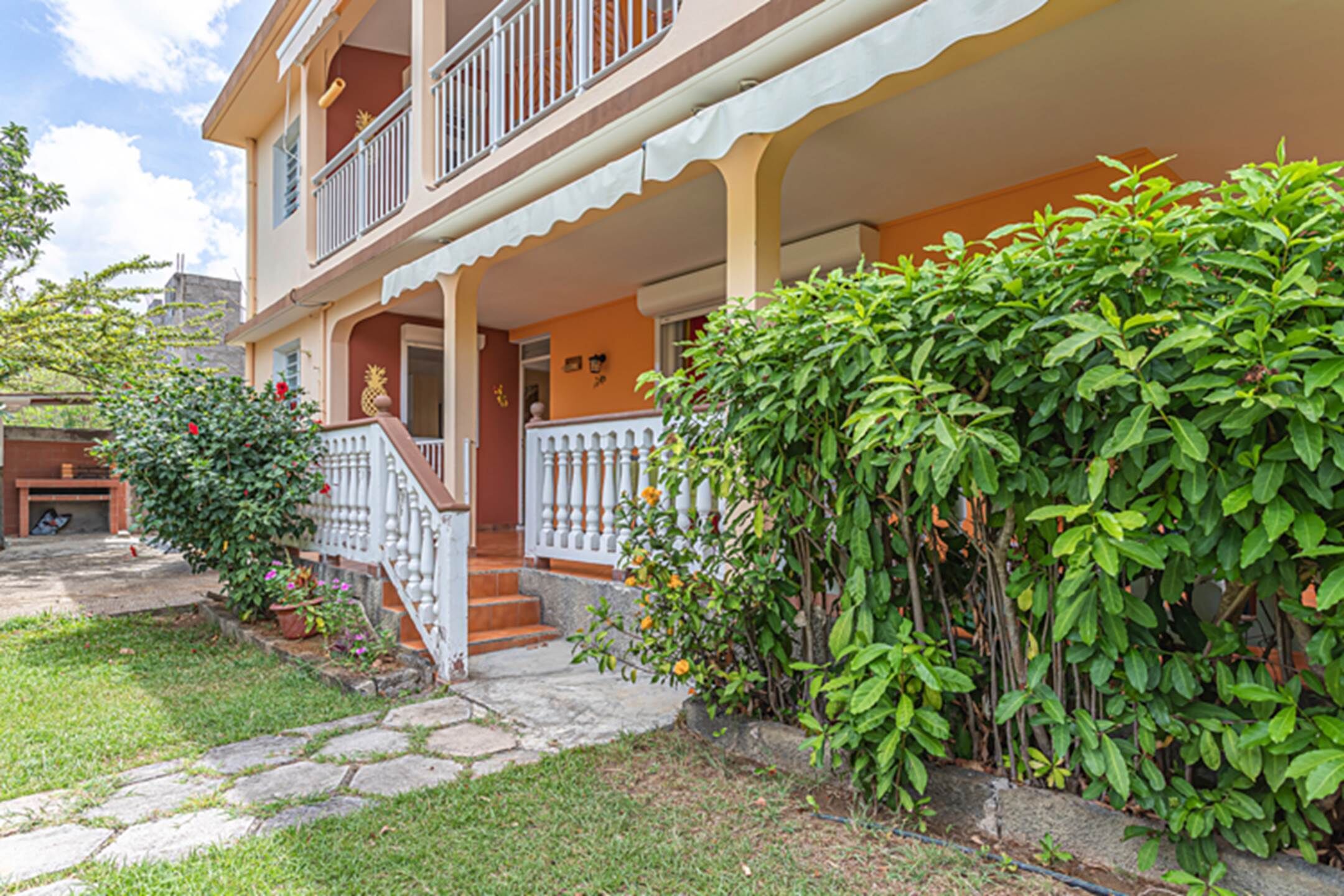 A two-story house with a balcony, a stone pathway, and a well-maintained garden.