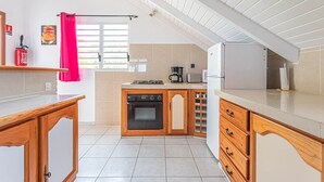 Een kleine keuken met houten kastjes, een inbouwoven en een koffiezetapparaat.