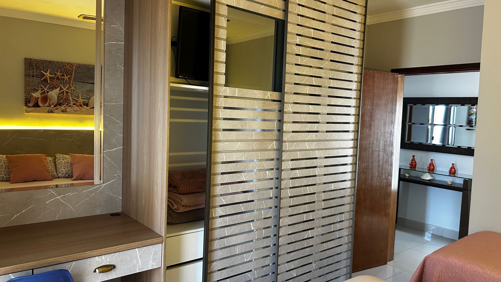Een moderne slaapkamer met een inbouwkast, nachtkastje en uitzicht op de keuken.