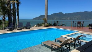 Una piscina con sillas de descanso y vista al océano.