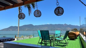 A terrace with a view of a lake and mountains, furnished with green chairs and a table. - Casa Praia das Cigarras (Sao Sebastiao)