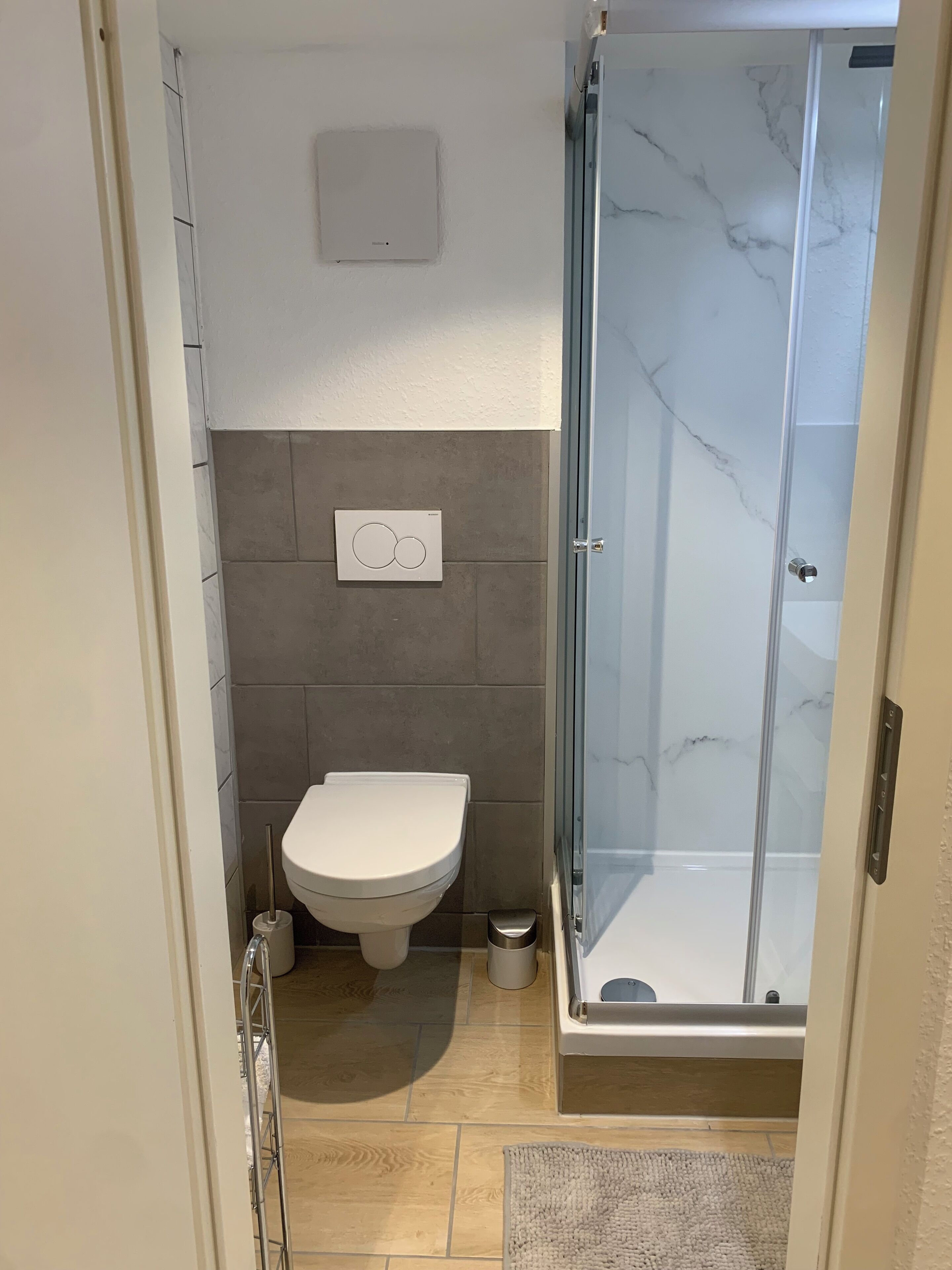 A bathroom with a toilet, a shower with a glass door, and a tiled floor.