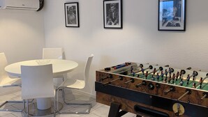 Ein modernes Zimmer mit einem Tischkicker, einem Esstisch mit Stühlen und drei gerahmten Bildern an der Wand.