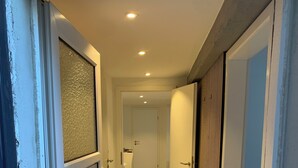 Ein Flur mit Fliesenboden, der zu einem Badezimmer mit Toilette und Waschbecken führt.