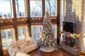 A cozy room with a large Christmas tree, a fireplace, and a sofa. - Mountain Jam (Morganton)