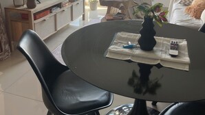A modern living room with a flat-screen TV, a dining table with chairs, a sofa, and a large window offering a city view. - MORON GRAN ATARDECER APARTMENT (Morón)