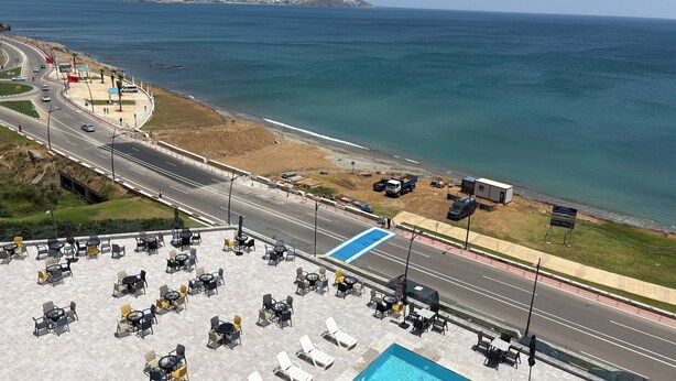 Un hôtel situé sur la côte, doté d’une piscine, d’un espace extérieur aménagé et offrant une vue sur la mer et une route.