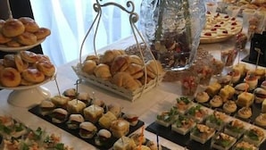 Une table de buffet proposant divers plats, notamment des sandwichs, des pâtisseries et des amuse-gueules.
