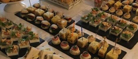 A buffet table with various food items including sandwiches, pastries, and appetizers.