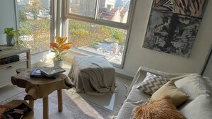 A modern living room with a large window, a sofa, a coffee table, and a painting on the wall. - MORON GREAT SUNSET (Morón)