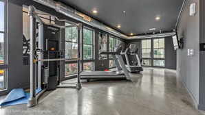 A gym with exercise equipment, large windows, and a concrete floor. - Modern Loft Retreat Steps from Memphis Hotspots (Memphis)