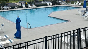 A swimming pool with lounge chairs and umbrellas, surrounded by a fence. - Ground floor, poolside unit #143. Beach and sound access. Great getaway! (Atlantic Beach)