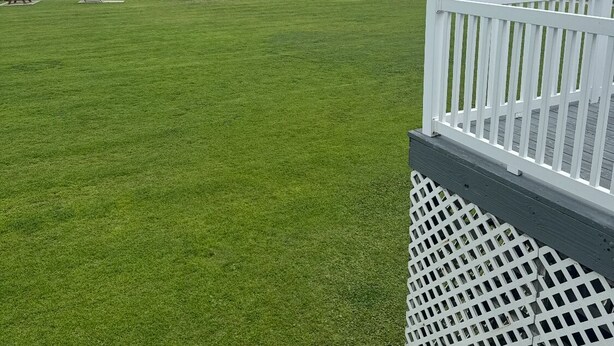 A grassy area with a dock extending into a body of water, a white fence, and a utility pole. - Ground floor, poolside unit #143. Beach and sound access. Great getaway! (Atlantic Beach)