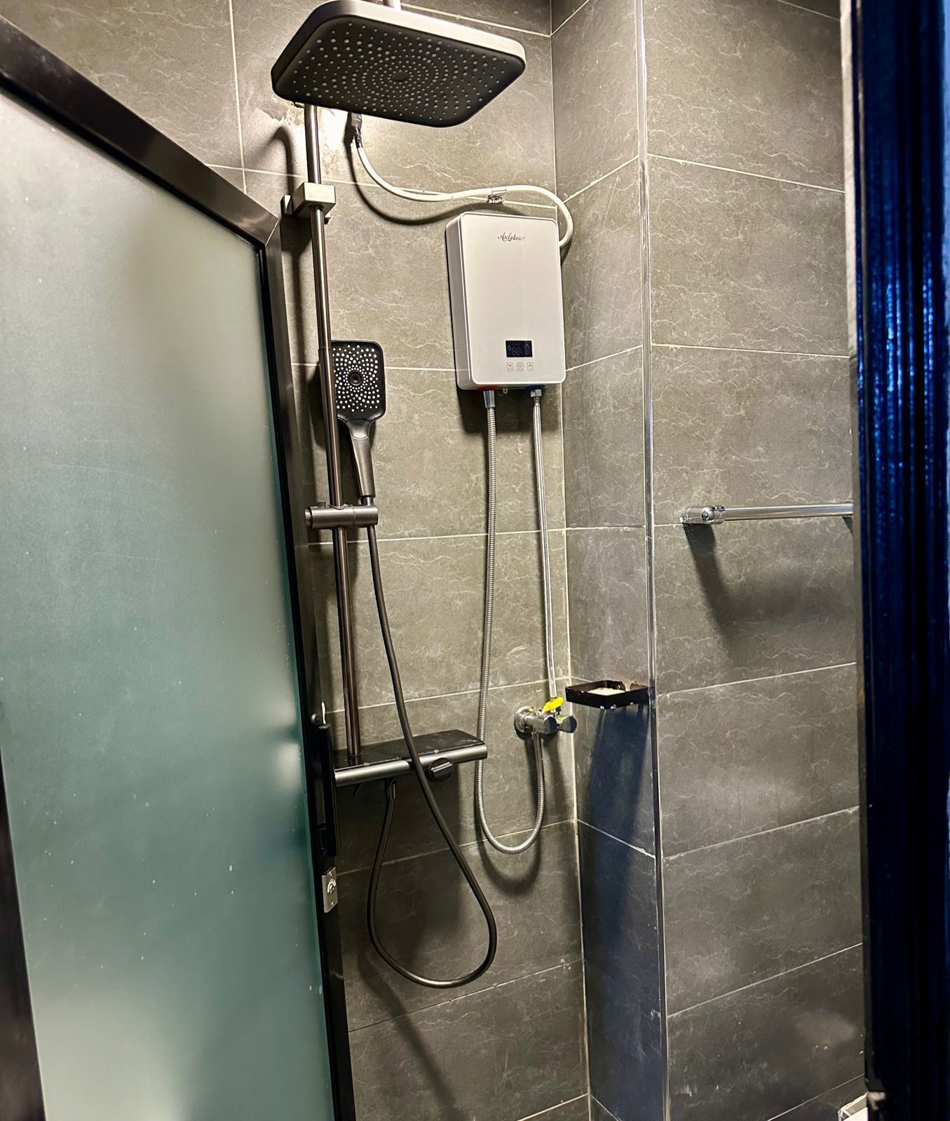 A shower with a handheld showerhead, a fixed showerhead, and a control panel.