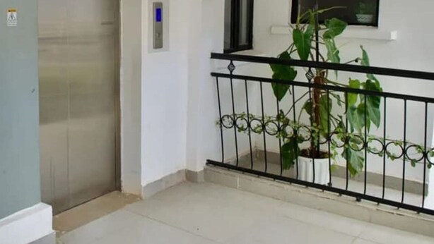 A clean, modern interior with a metal railing, a potted plant, and a fire extinguisher mounted on the wall. - Triad Apartment (Nairobi)