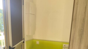 A small bathroom with a green shelf, a white cabinet, and a door leading to a balcony. - Duplex 6 pers 55m2 with swimming pool and sea nearby (Saint-Raphaël)
