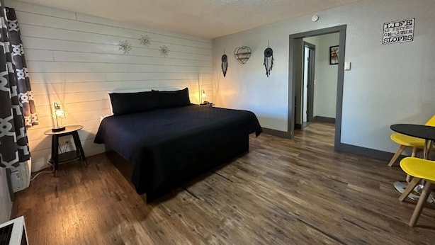 Une chambre à coucher avec un lit, des lampes de chevet, un mur décoré d’attrape-rêves, une porte et un panneau.