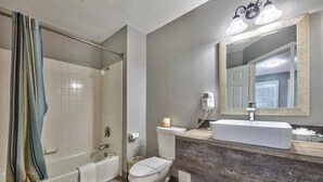 Une salle de bain avec une baignoire, des toilettes et un meuble-lavabo avec un miroir.