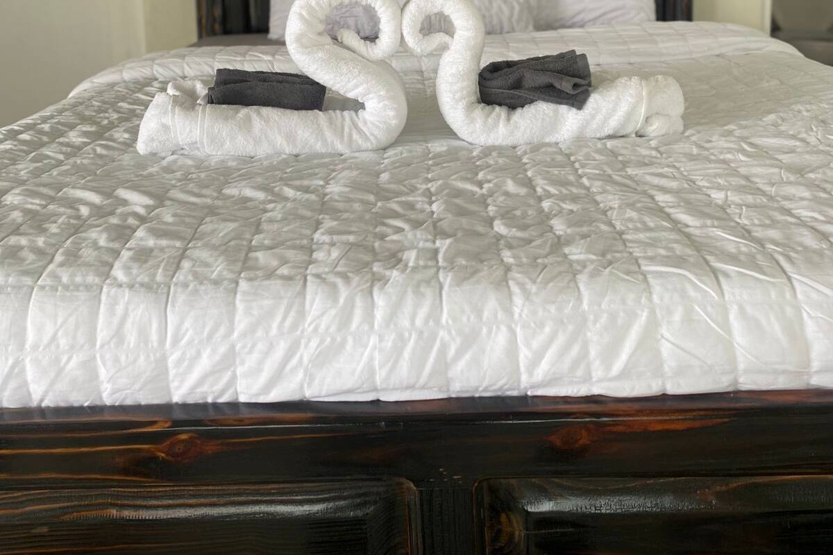 Un lit bien fait, recouvert d’une couette blanche, avec deux serviettes disposées en forme de cygne.