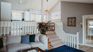 Un espacio habitable amplio con techo alto, una escalera y vistas a la cocina.