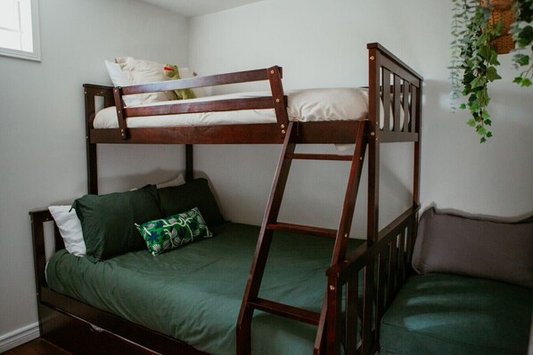 A bunk bed with a ladder, a green sofa, and a pillow with a floral pattern.