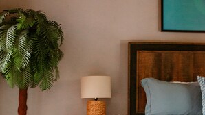 Un dormitorio con una mesita de noche de madera, una lámpara, una cama con ropa de cama azul y una alfombra azul.