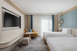 A hotel room with a TV, two beds, a sofa, a small table, and a large window with curtains. - Doubletree By Hilton Tashkent (Tashkent)