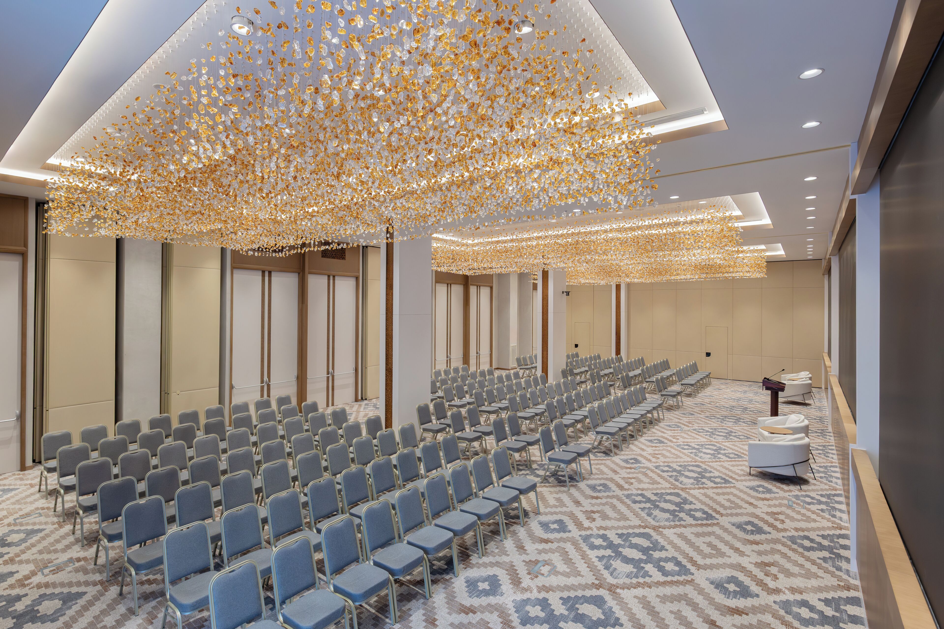 A conference room with rows of chairs, a patterned carpet, and a ceiling with hanging decorations.