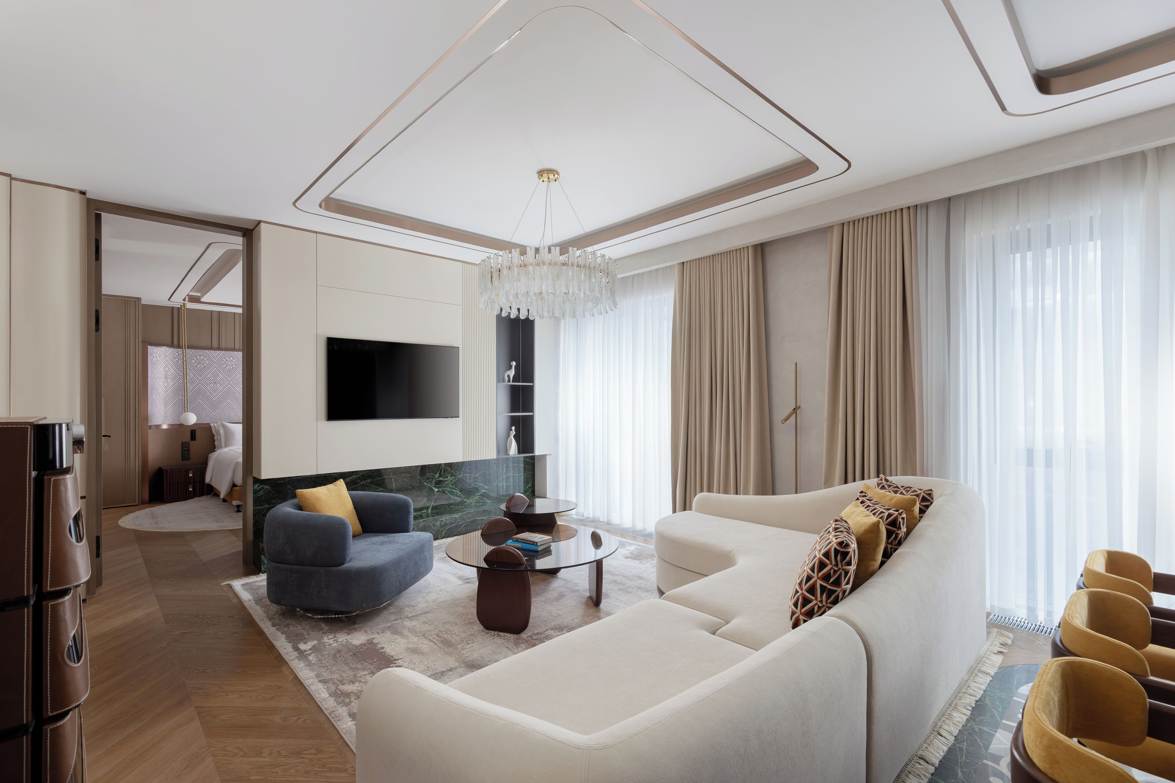 Un salon moderne comprenant un canapé, un fauteuil, une table basse et un téléviseur fixé au mur.