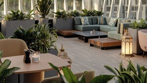 A modern outdoor lounge area with seating, planters, and a decorative lantern. - Doubletree By Hilton Tashkent (Tashkent)