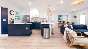 A modern kitchen with white cabinets, a central island, stainless steel appliances, and pendant lighting.