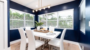 A dining area with a white table, four white chairs, and a ceiling light fixture.