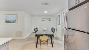 A modern kitchen with a dining table, chairs, and a refrigerator.