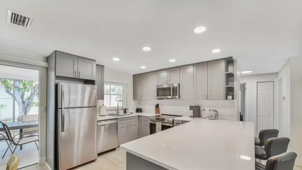 A modern kitchen with stainless steel appliances, white cabinetry, and a central island.