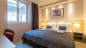 A hotel room with a bed, bedside tables, a desk, and a window with curtains. - Villa Molunat 4 (Molunat)