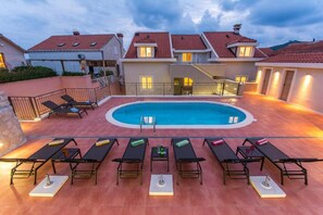 A swimming pool with lounge chairs and a covered patio area.