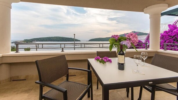 Eine Terrasse mit Tisch, Stühlen, einer Weinflasche und Gläsern.