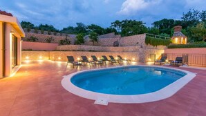 A swimming pool with lounge chairs and a stone wall in the background. - Villa Molunat 9 (Molunat)