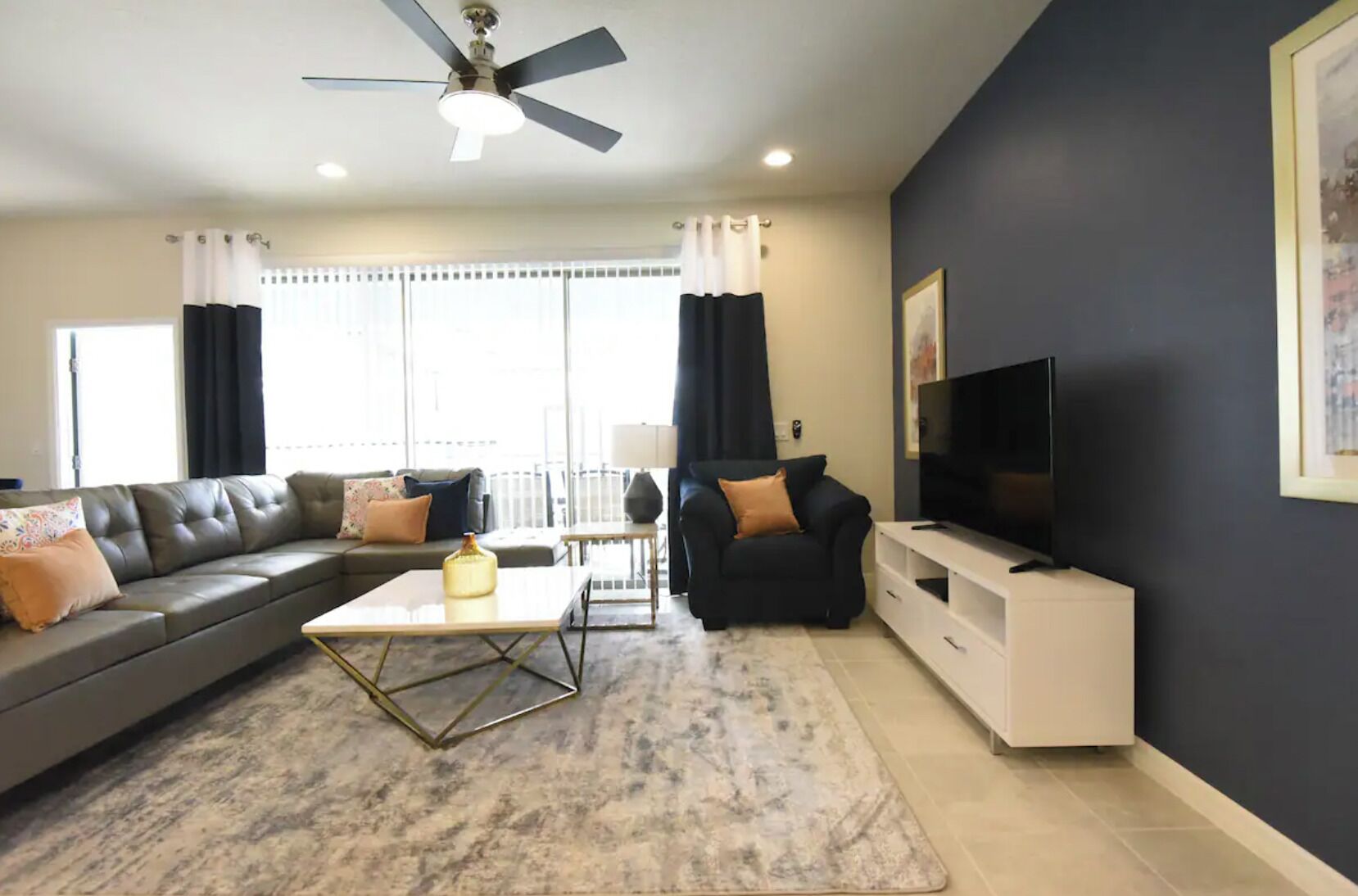 A modern living room with a sofa, armchair, coffee table, and TV stand.