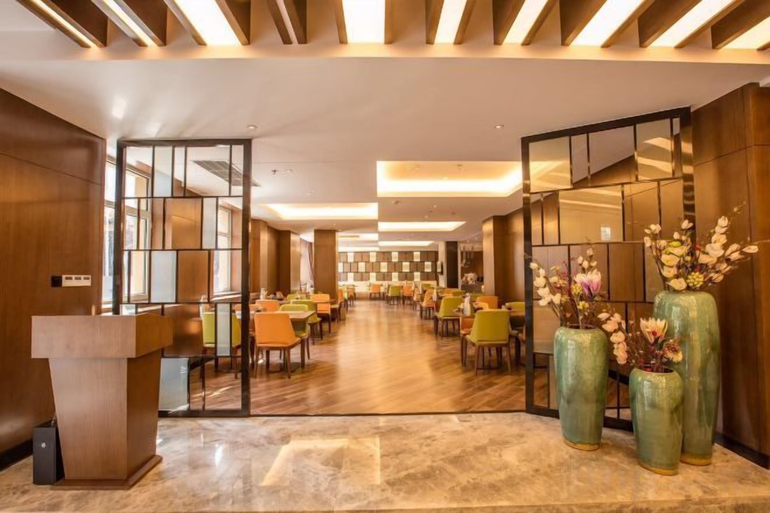 Un vestíbulo de hotel con mostrador de recepción, zona de estar y grandes jarrones decorativos.