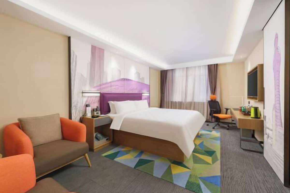 A hotel room with a bed, a sofa, a desk, and a chair.